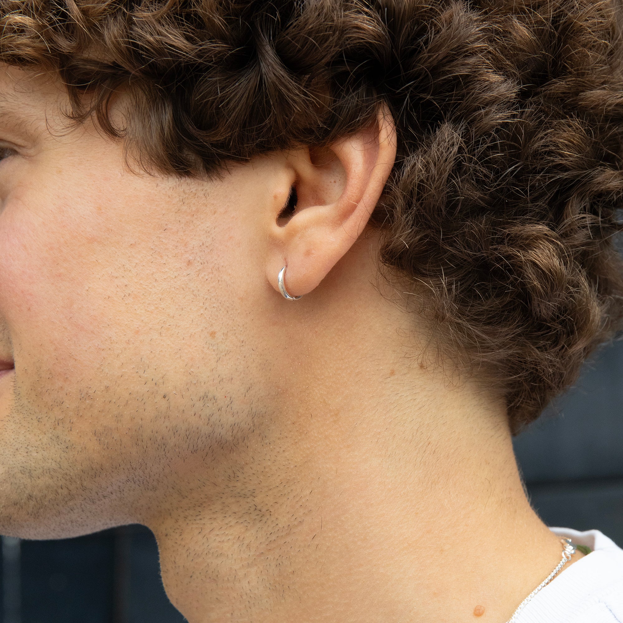 Close-up of a person's ear with a small earring - small silver hoop earring - seolgold