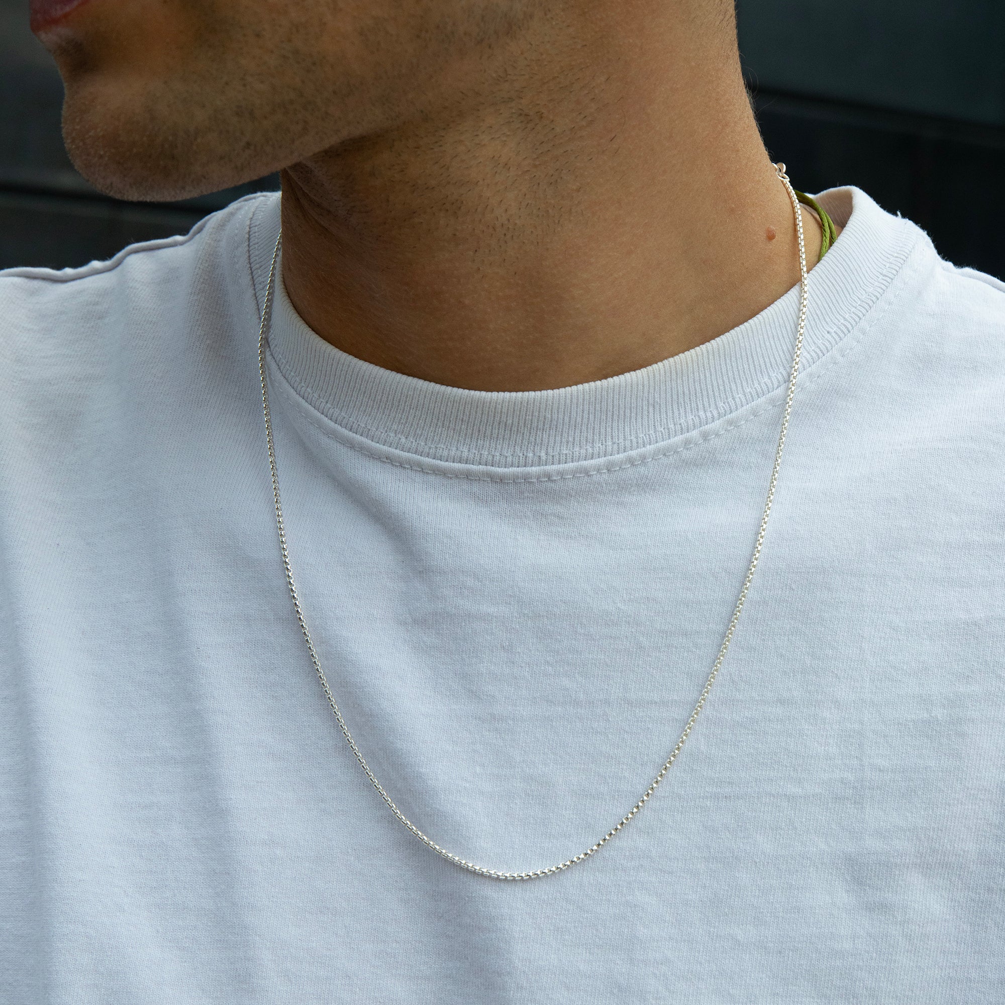 Person wearing a silver chain necklace on a plain background - seolgold