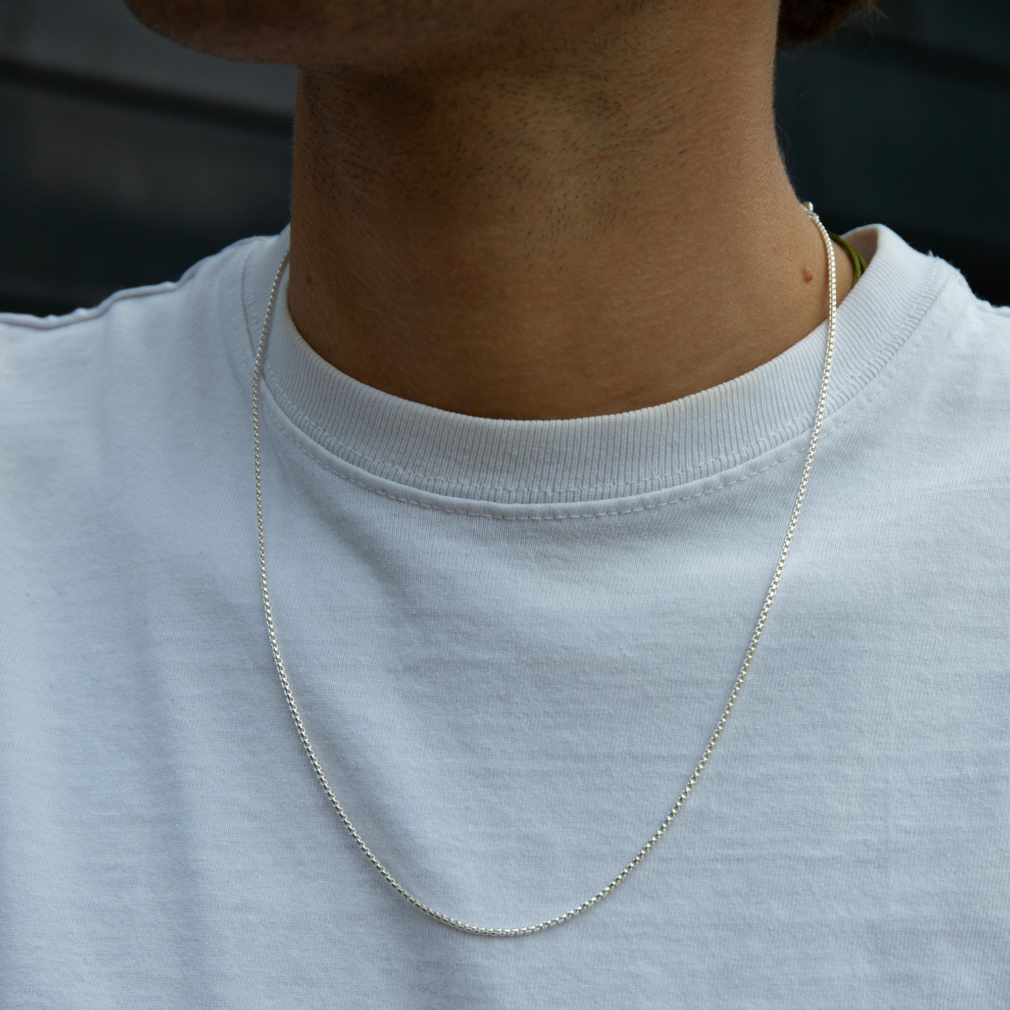 Person wearing a silver chain necklace on a plain background - seolgold