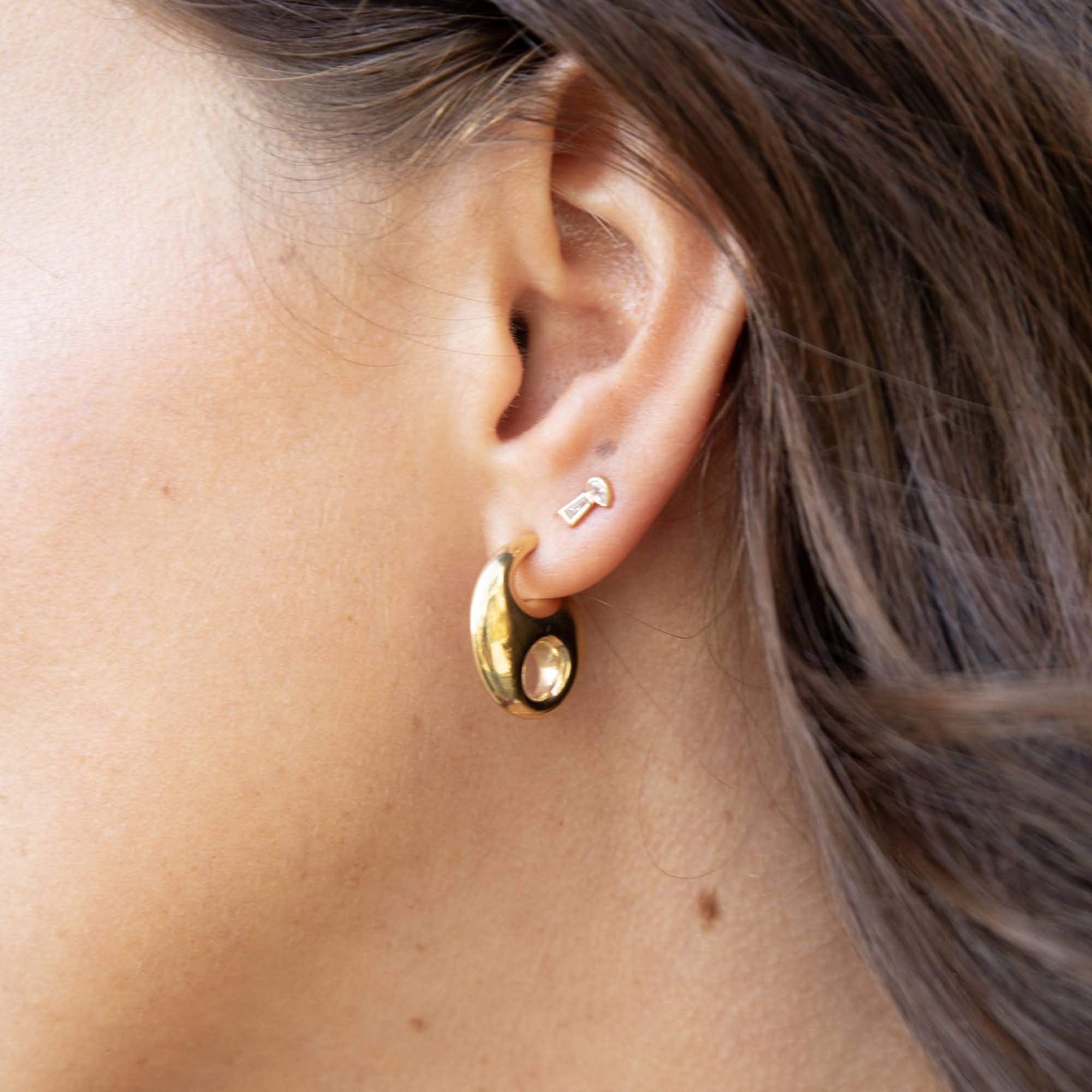 Close-up of a person wearing gold hoop earrings - seol gold