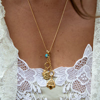Gold necklace with charms on a person wearing a white lace garment - gold box chain - seolgold
