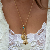 Gold necklace with charms on a person wearing a white lace garment - seolgold