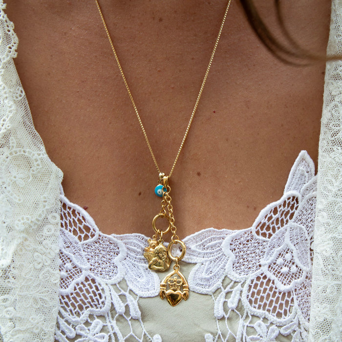Gold necklace with charms on a person wearing a white lace garment - seolgold