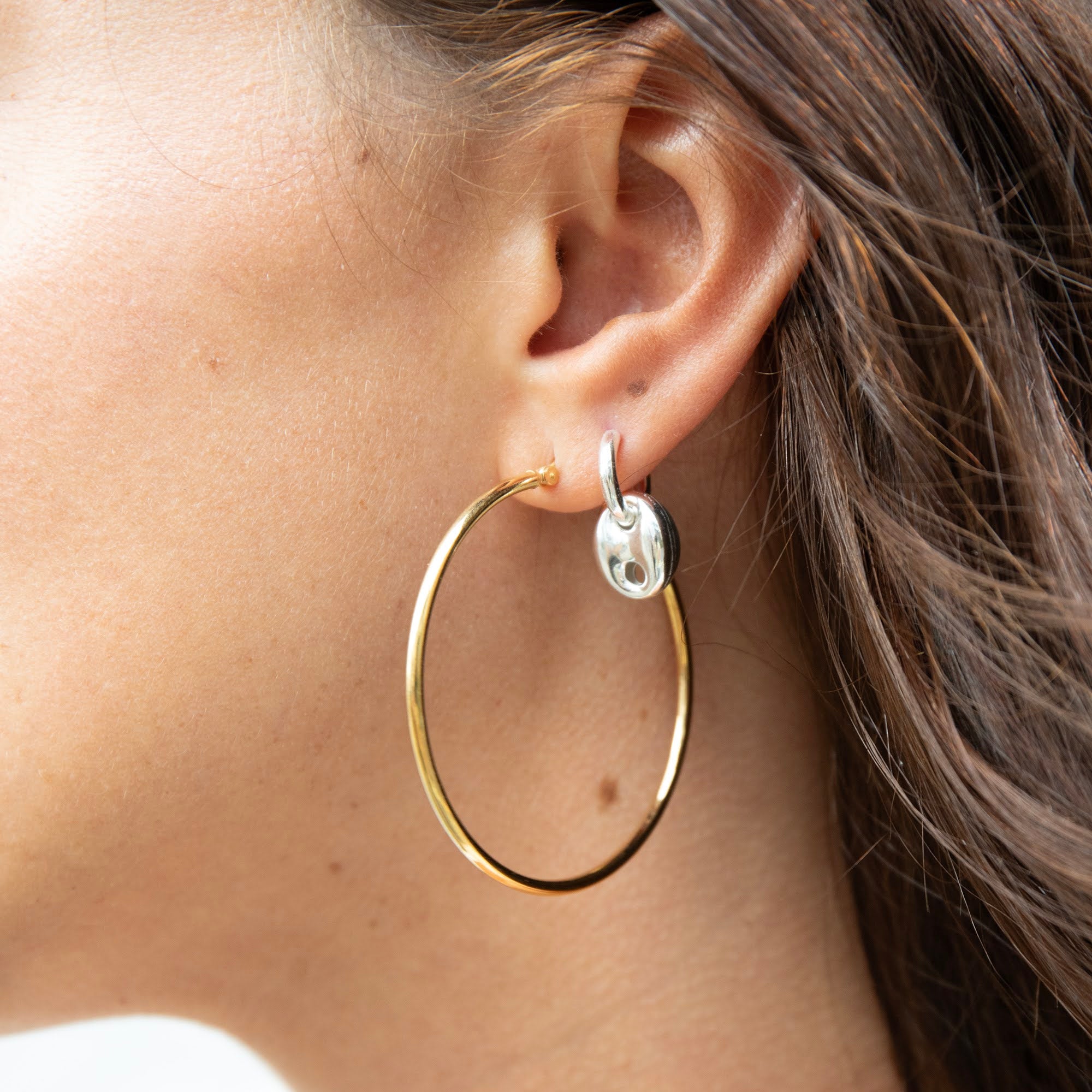 Close-up of a person wearing gold hoop earrings with a silver accent - seolgold
