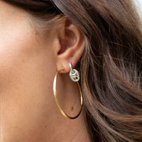 Gold hoop earring with a small round charm worn by a person - seolgold