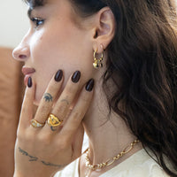Close-up of a woman's hand and ear with gold jewelry - Seol Gold
