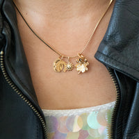 Gold necklace with charms worn by a person in a black leather jacket - seolgold