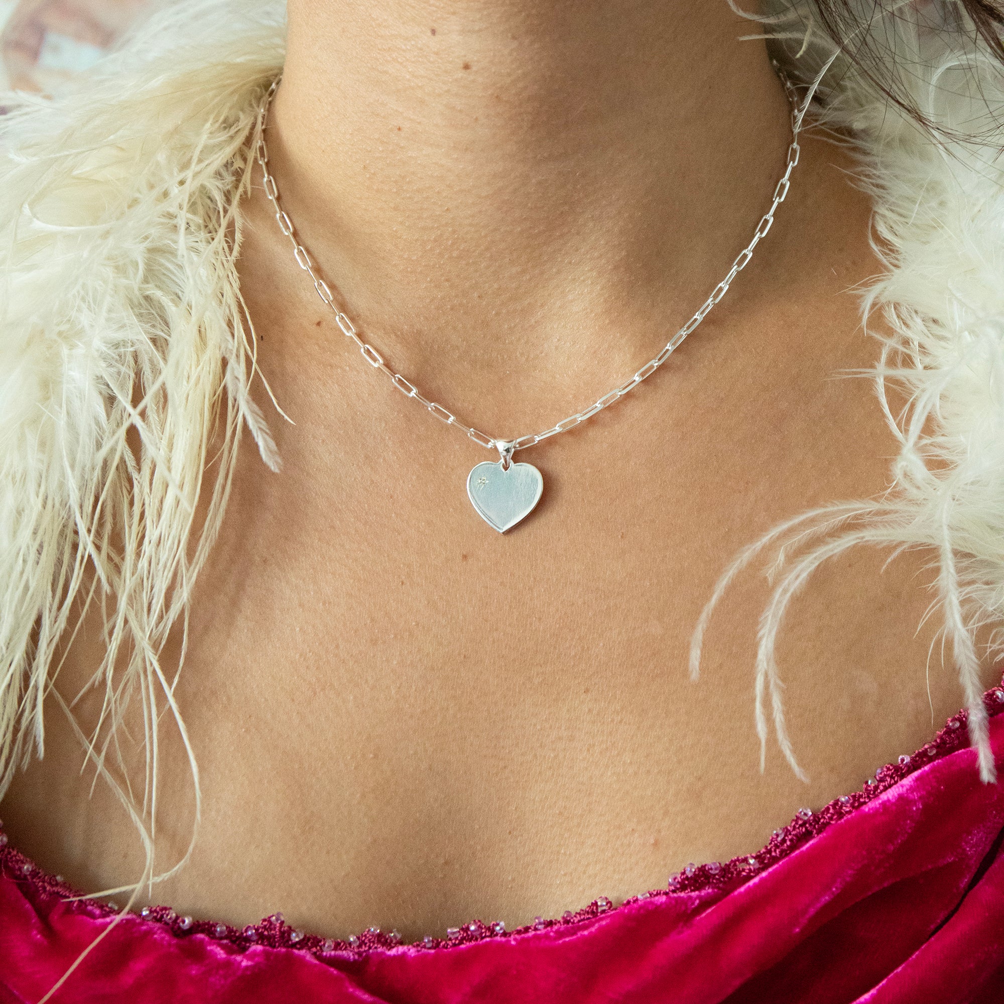 Necklace with a heart pendant worn by a person with white feathers in the background - seolgold