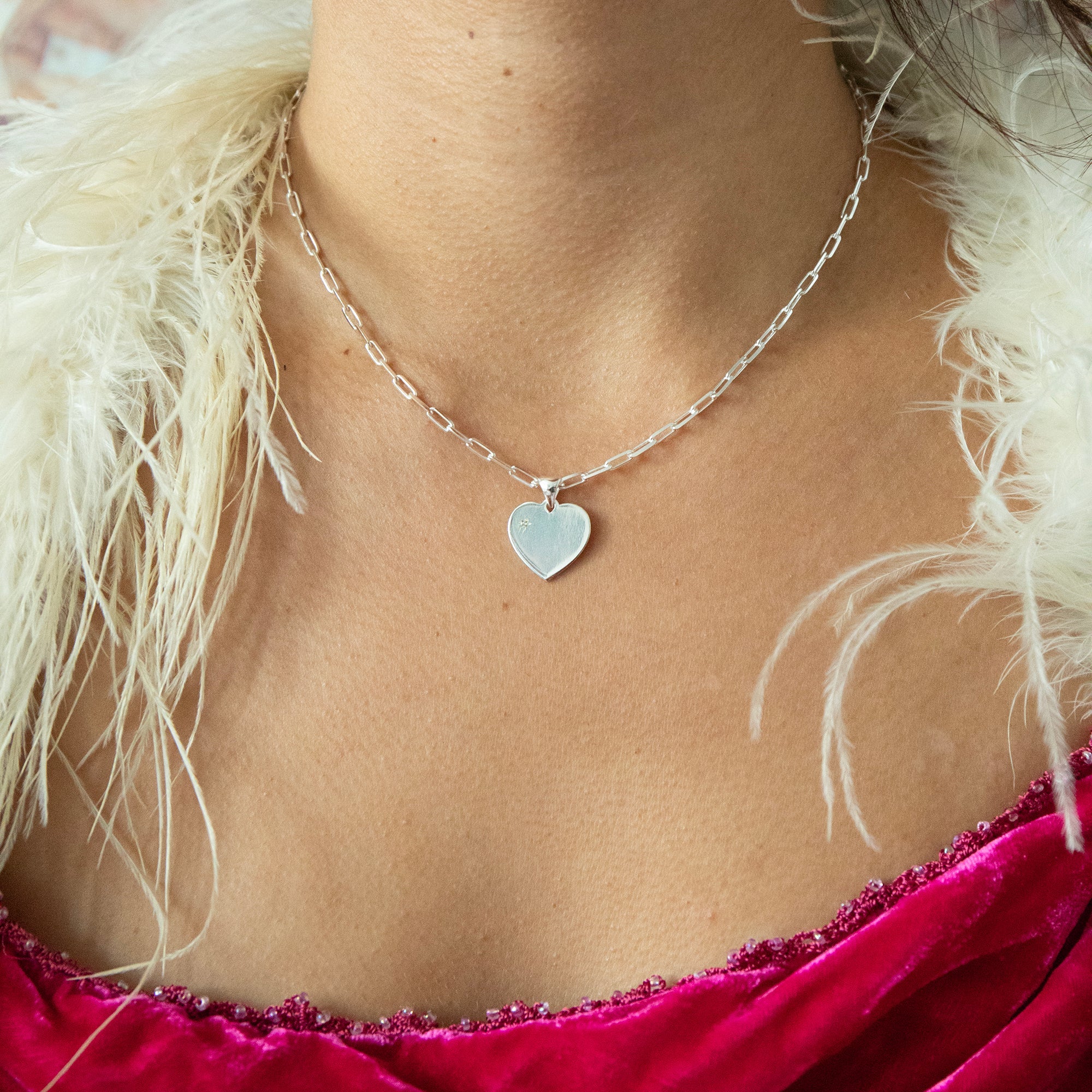 Necklace with a heart pendant worn by a person with white feathers in the background - seolgold