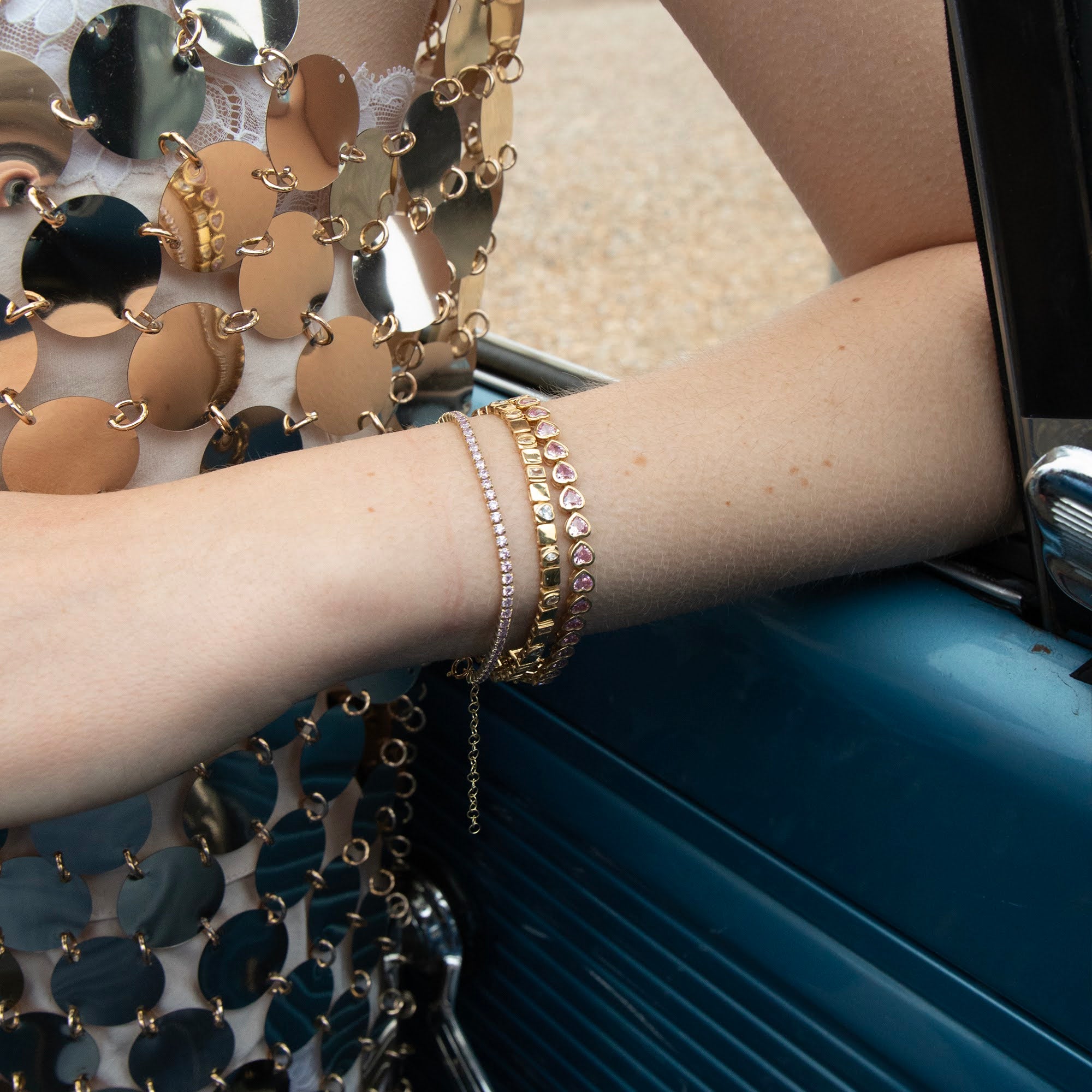 Close-up of a person's arm wearing gold bracelets with a reflective surface in the background - seolgold