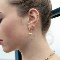 Close-up of a woman's ear wearing gold earrings with a blurred background - seolgold