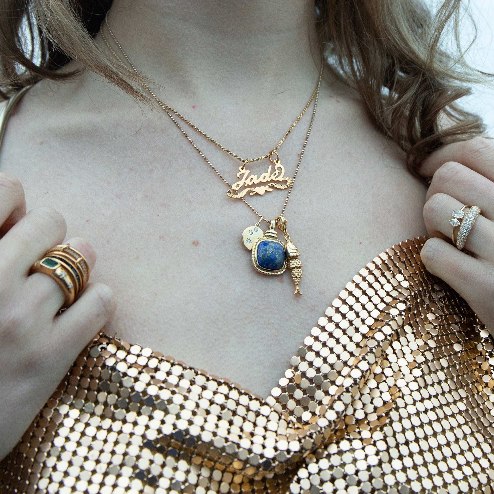 Close-up of a person wearing gold necklaces and rings with a gold sequin top - seolgold