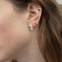 Close-up of an ear wearing multiple silver and gemstone earrings with visible jewelry  - seolgold
