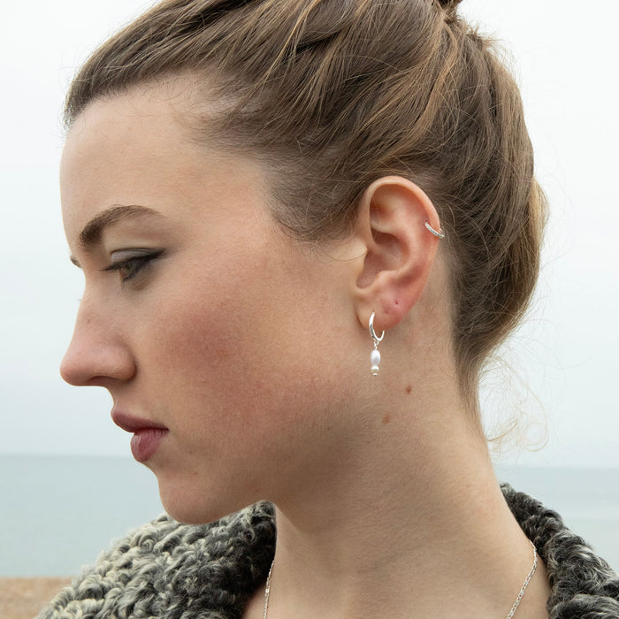 Close-up of a woman wearing a silver earring with a blurred background - seolgold