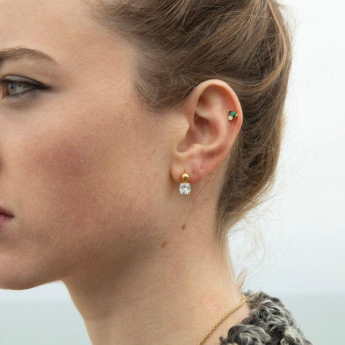 Close-up of a woman's ear wearing gold and silver earrings with a neutral background - seolgold