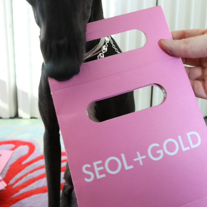 Pink product packaging with 'SEOL+GOLD' branding held by a person - seolgold