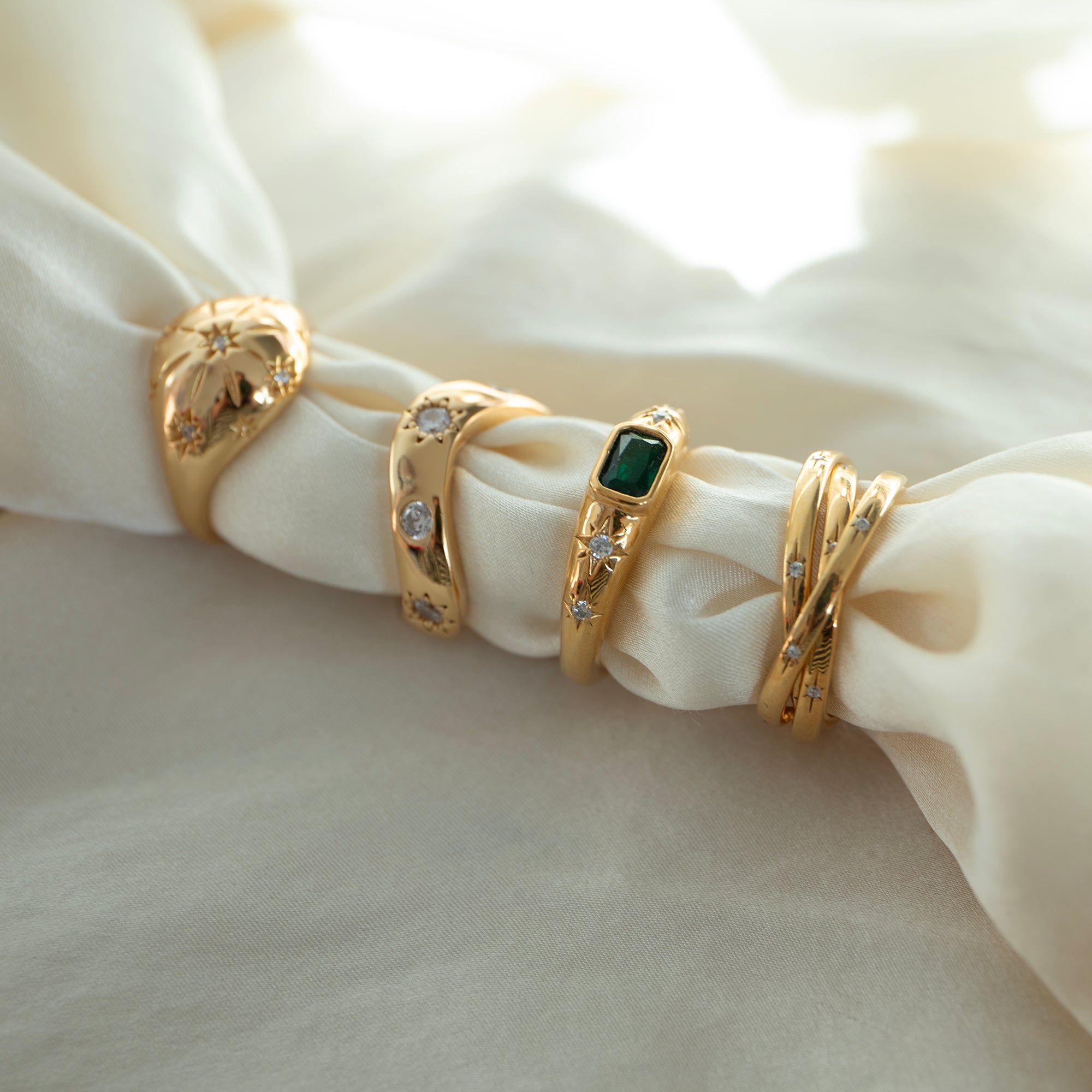 Set of gold rings with gemstones on a white fabric background - seolgold