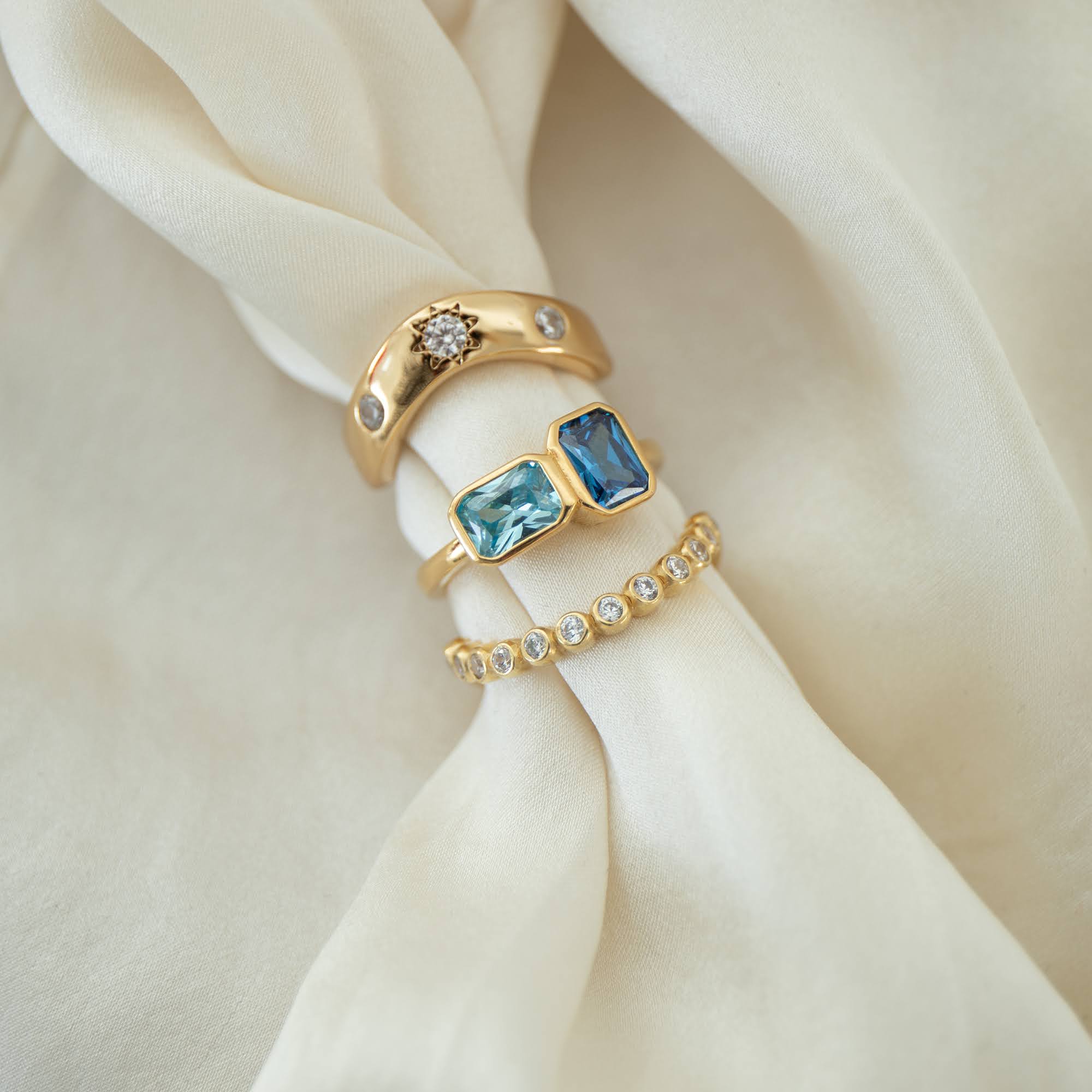 Gold rings with blue gemstones and small diamonds on a beige fabric - seolgold 