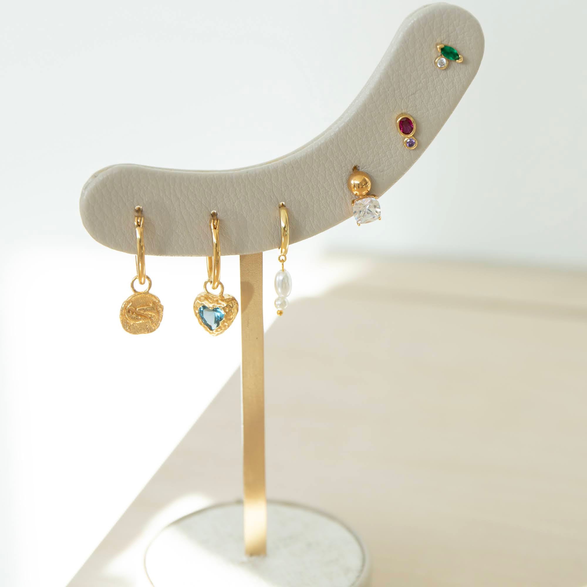 Set of gold earrings on a stand with a light background - seolgold