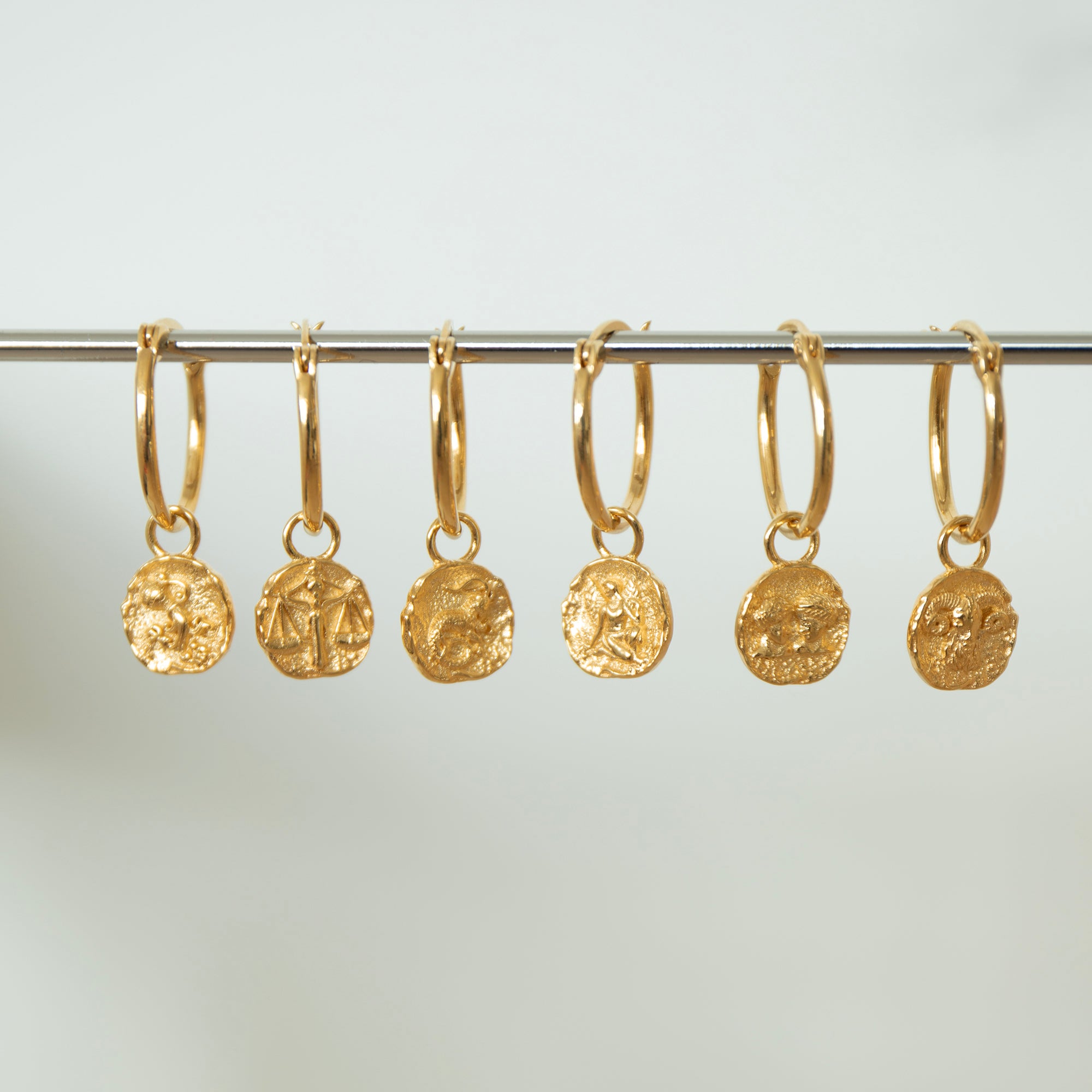 Set of gold hoop earrings with embedded coins on a gray background - seolgold