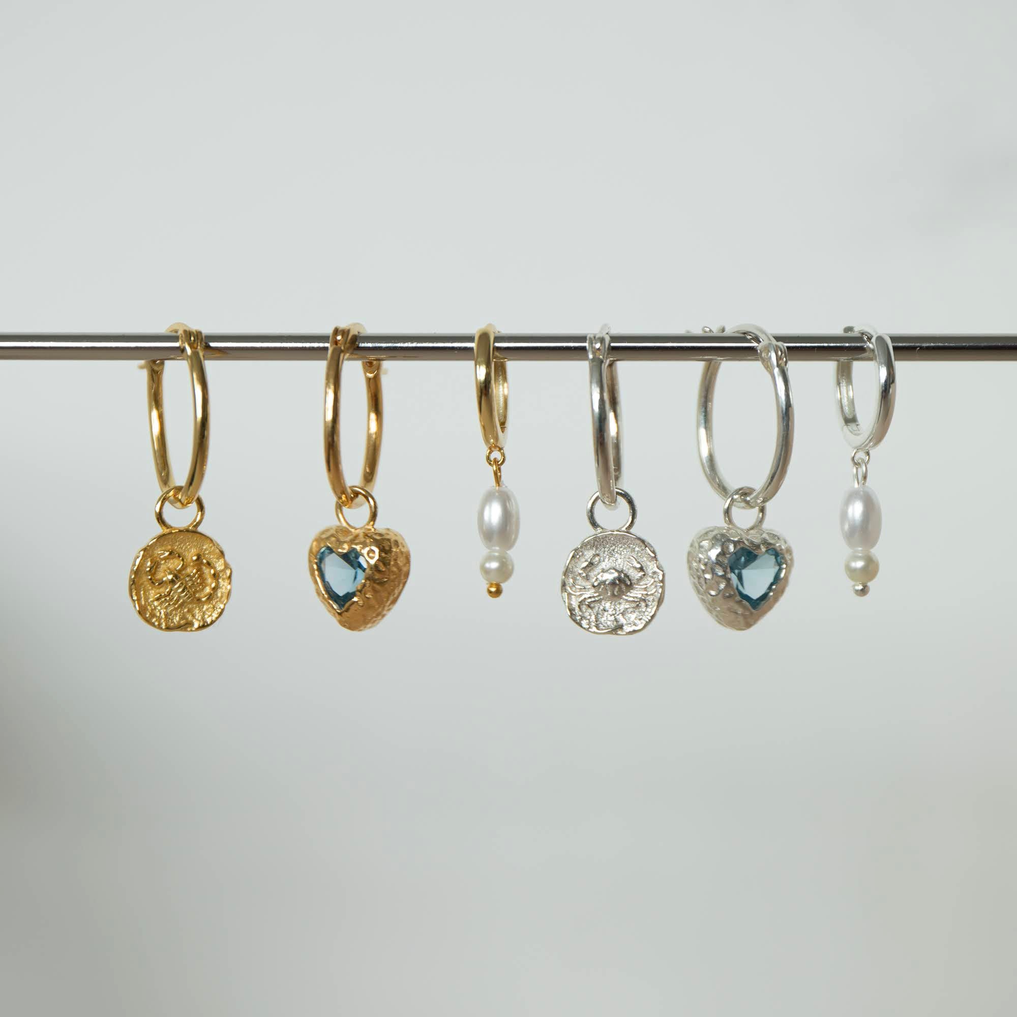 Set of gold and silver hoop earrings with various charms on a gray background - seolgold