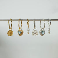Set of gold and silver hoop earrings with various charms on a gray background - seolgold