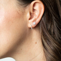 Close-up of an ear wearing a flower-shaped earring with a blurred background - seolgold