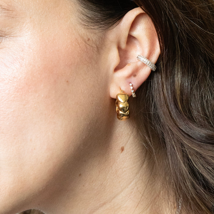 Close-up of an ear with gold hoop earrings and multiple silver studs - seolgold