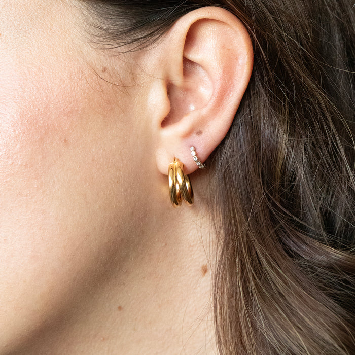Close-up of an ear wearing gold hoop earrings with a neutral background - seolgold