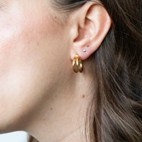 Close-up of an ear wearing gold hoop earrings with a neutral background - seolgold