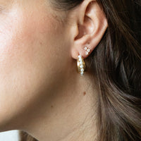 Close-up of an ear wearing gold hoop earrings with flower star-shaped studs - seolgold