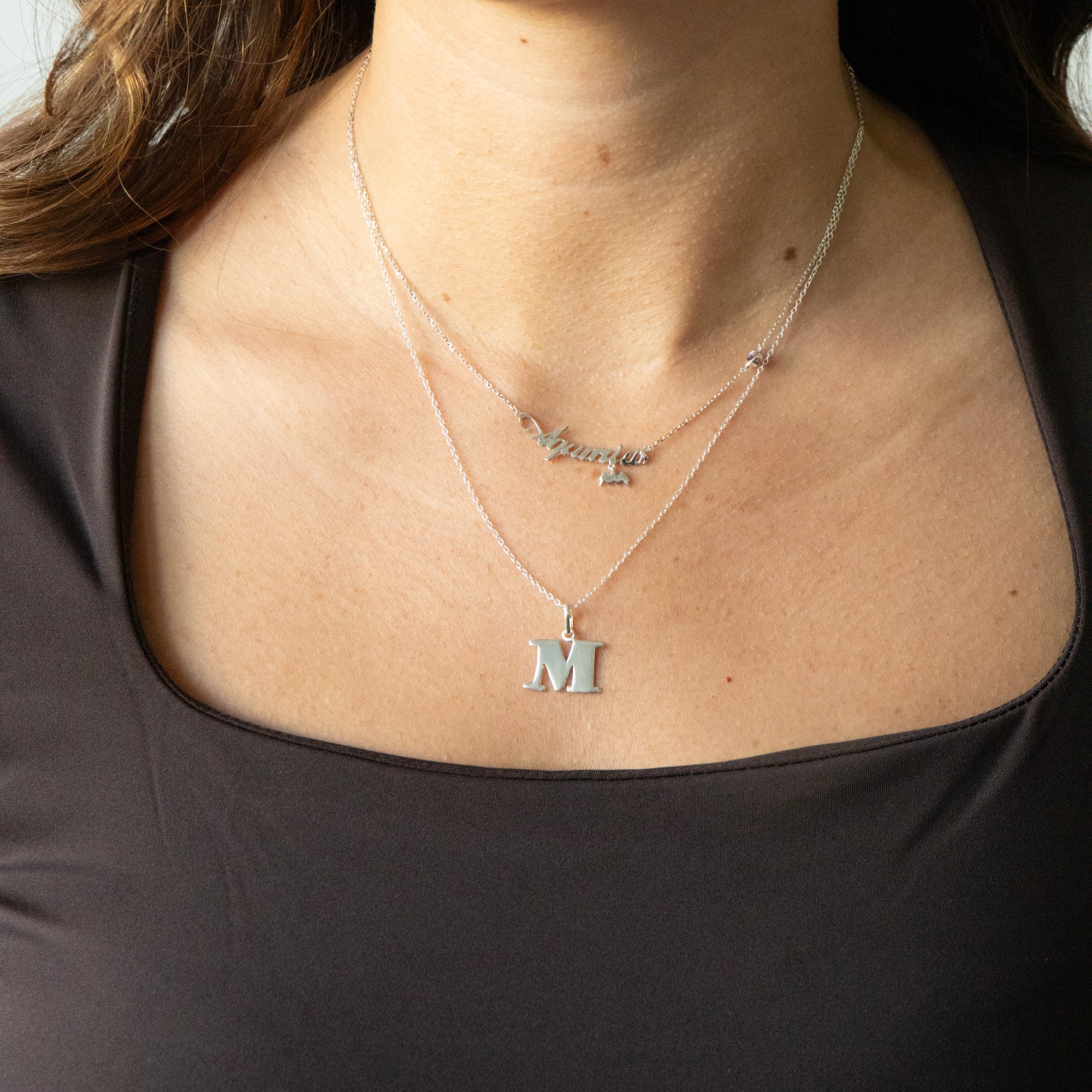 Necklace with a letter 'M' pendant on a person wearing a black top - seolgold