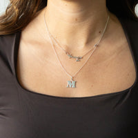 Necklace with a letter 'M' pendant on a person wearing a black top - seolgold