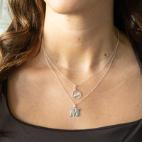 Close-up of a person wearing two silver necklaces with pendants - thin silver plain chain - seolgold