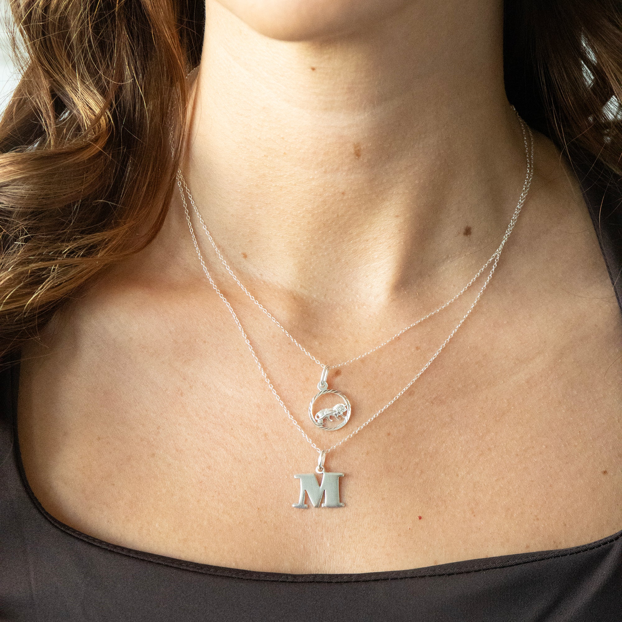 Close-up of a person wearing two necklaces with pendants on a plain background - seolgold