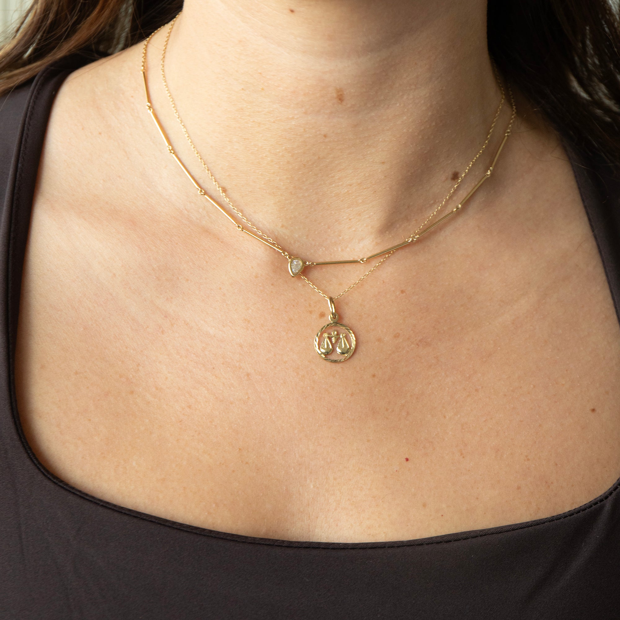 Gold necklace with a pendant on a person wearing a brown top - seolgold