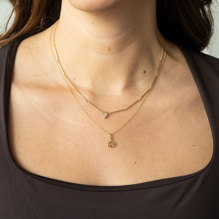 Close-up of a person wearing two gold necklaces with pendants - seolgold