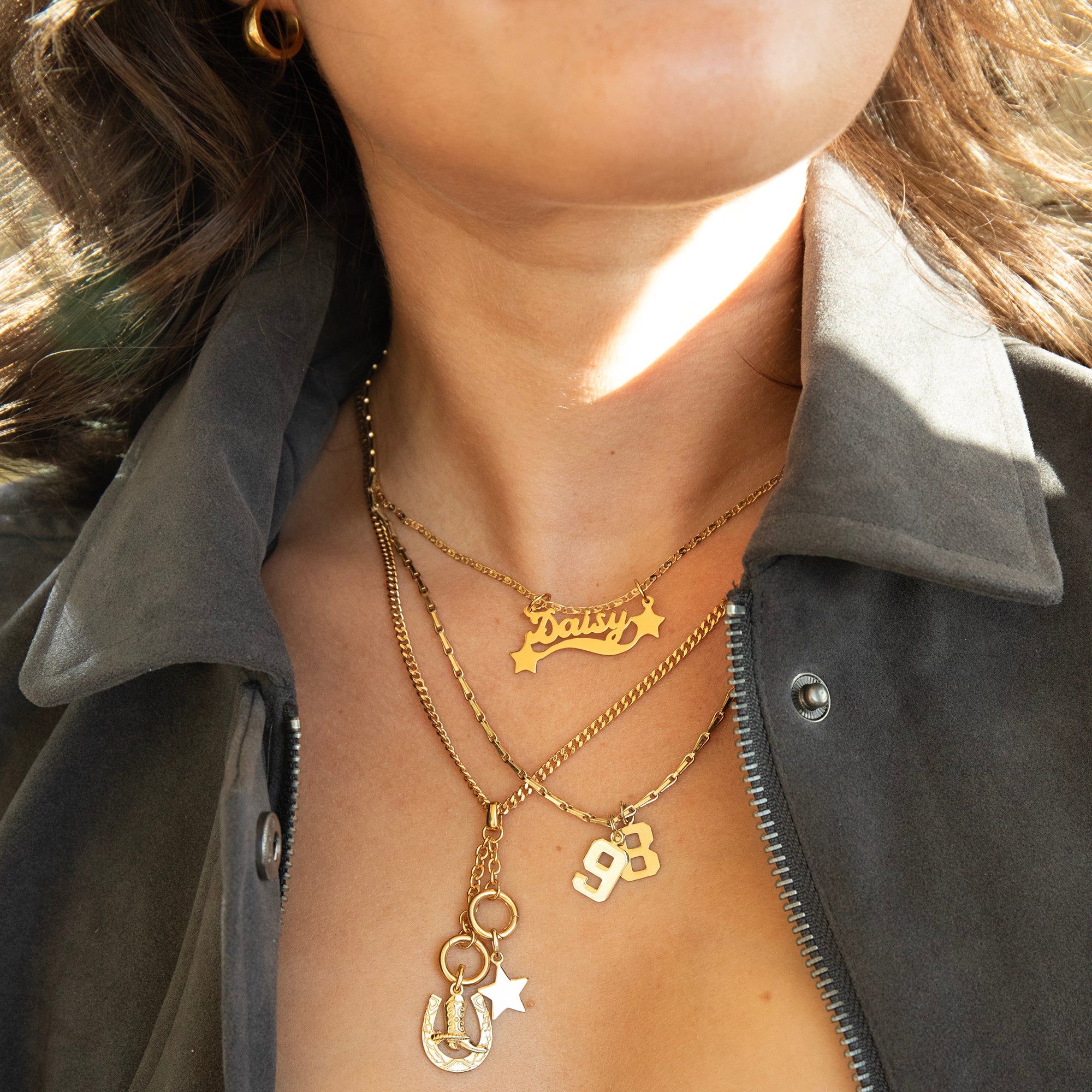 Close-up of a person wearing gold necklaces with 'Daisy' pendant and star charm - seolgold