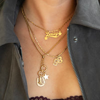 Gold necklaces with charms on a person wearing a gray jacket - seolgold