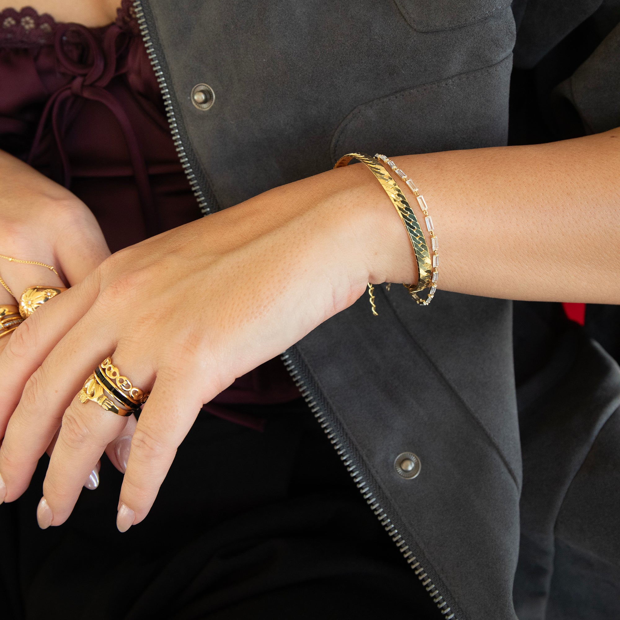 Close-up of hands wearing gold rings and bracelets against a dark background - seolgold