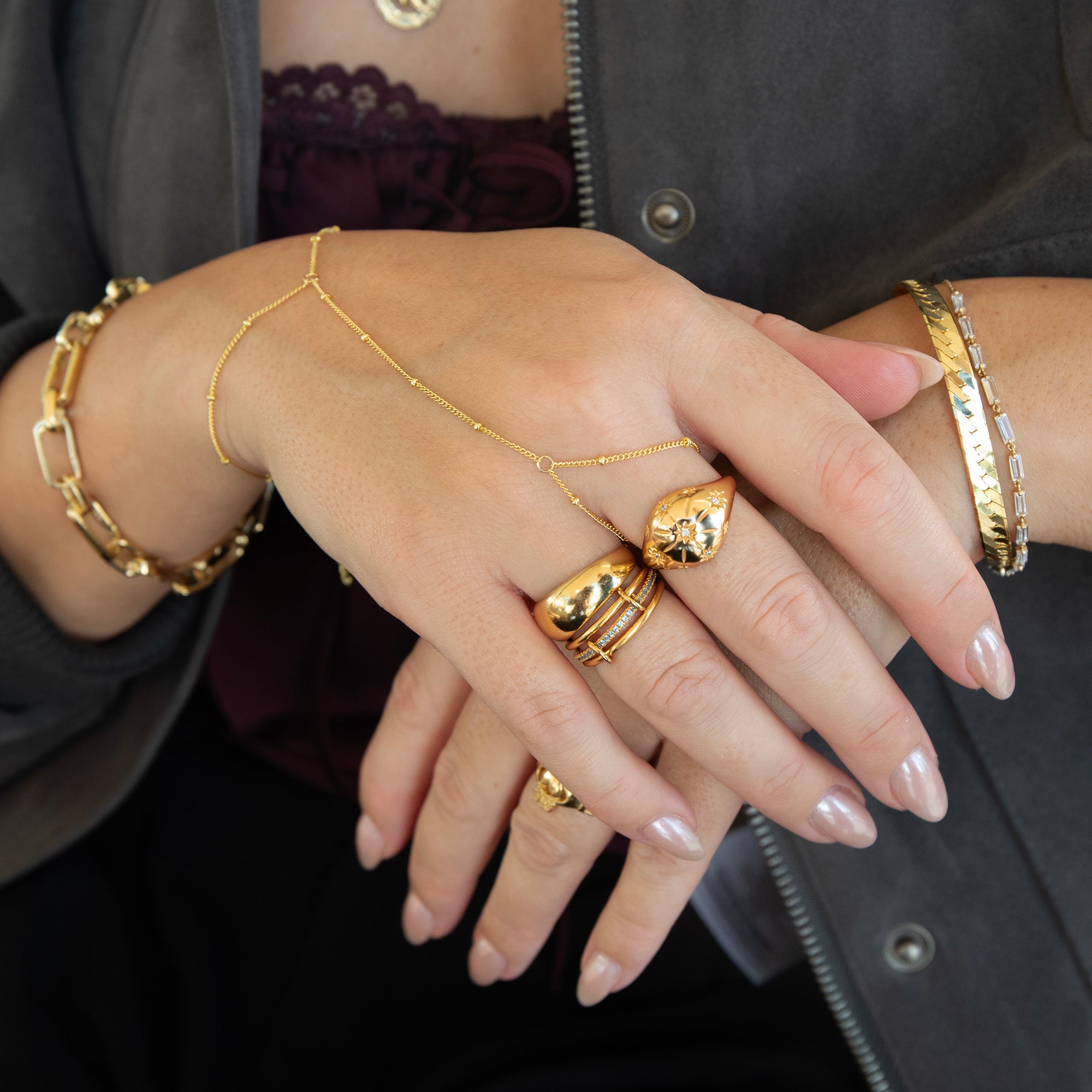Close-up of hands wearing gold jewelry with a dark background - seolgold