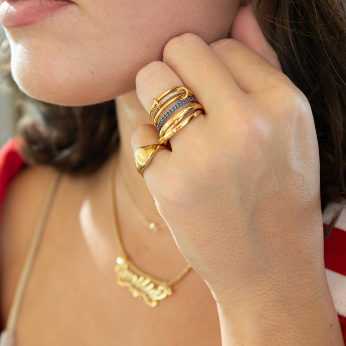 Close-up of a hand wearing multiple gold rings with a blurred background - seolgold