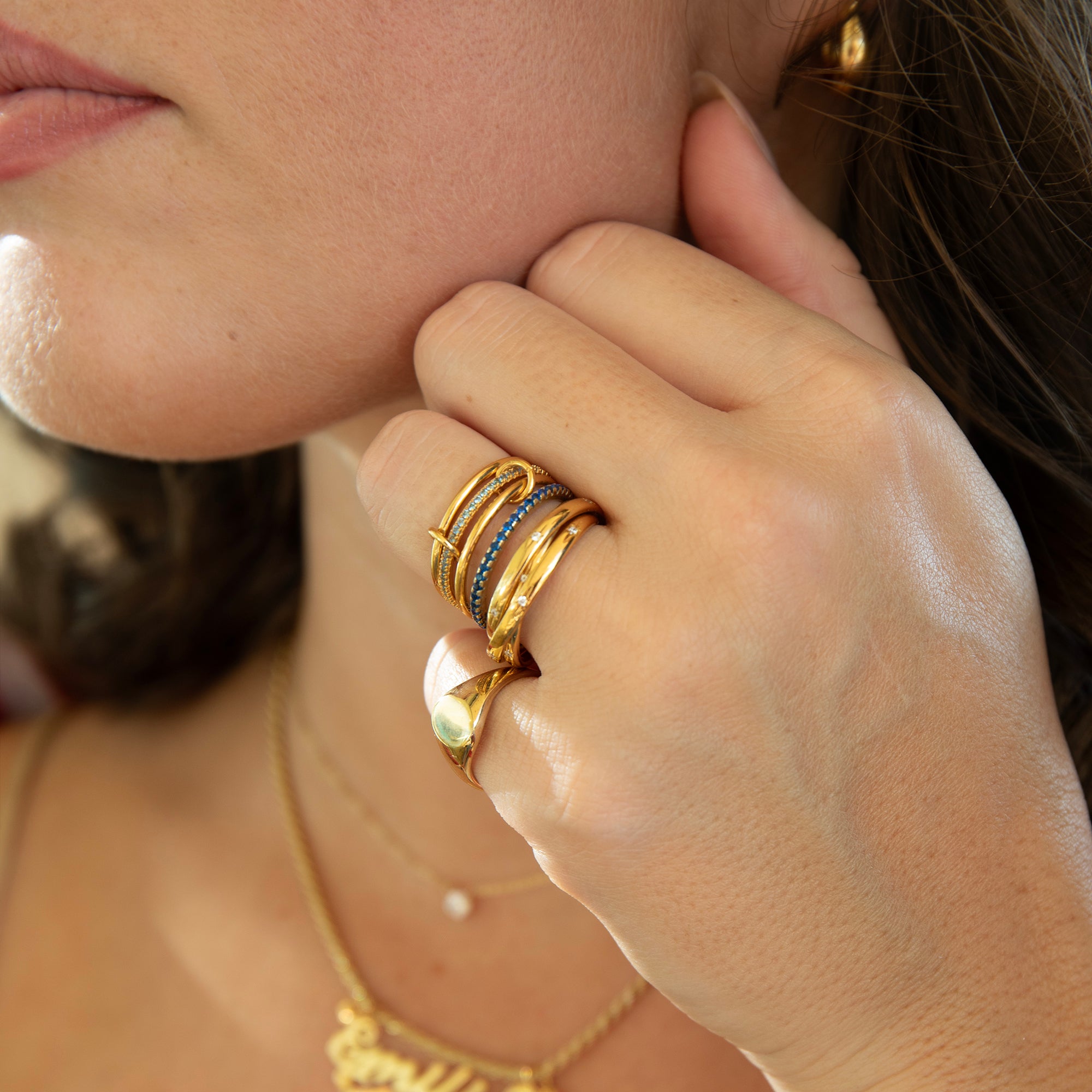 Close-up of a person wearing multiple gold rings on their finger - seolgold