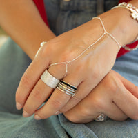 Close-up of hands wearing multiple rings and bracelets on a blurred background - seolgold