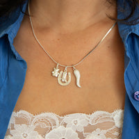 Necklace with horse shoe and boot charms worn by a person in a blue shirt and lace top - seolgold