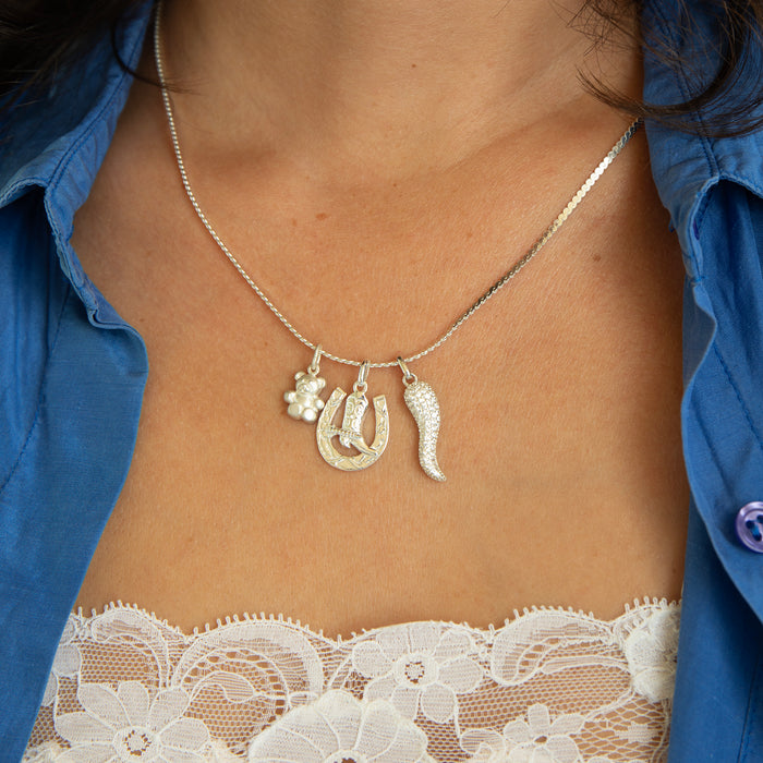 Necklace with horse shoe and boot charms worn by a person in a blue shirt and lace top - seolgold