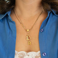 Gold necklace with heart and letter 'R' pendant worn by a person in a blue shirt - seolgold