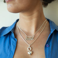 Person wearing a silver necklace with a heart pendant and another necklace with engraved name on a blue shirt - Sterling Silver Custom Script Star Name Pendant - seolgold