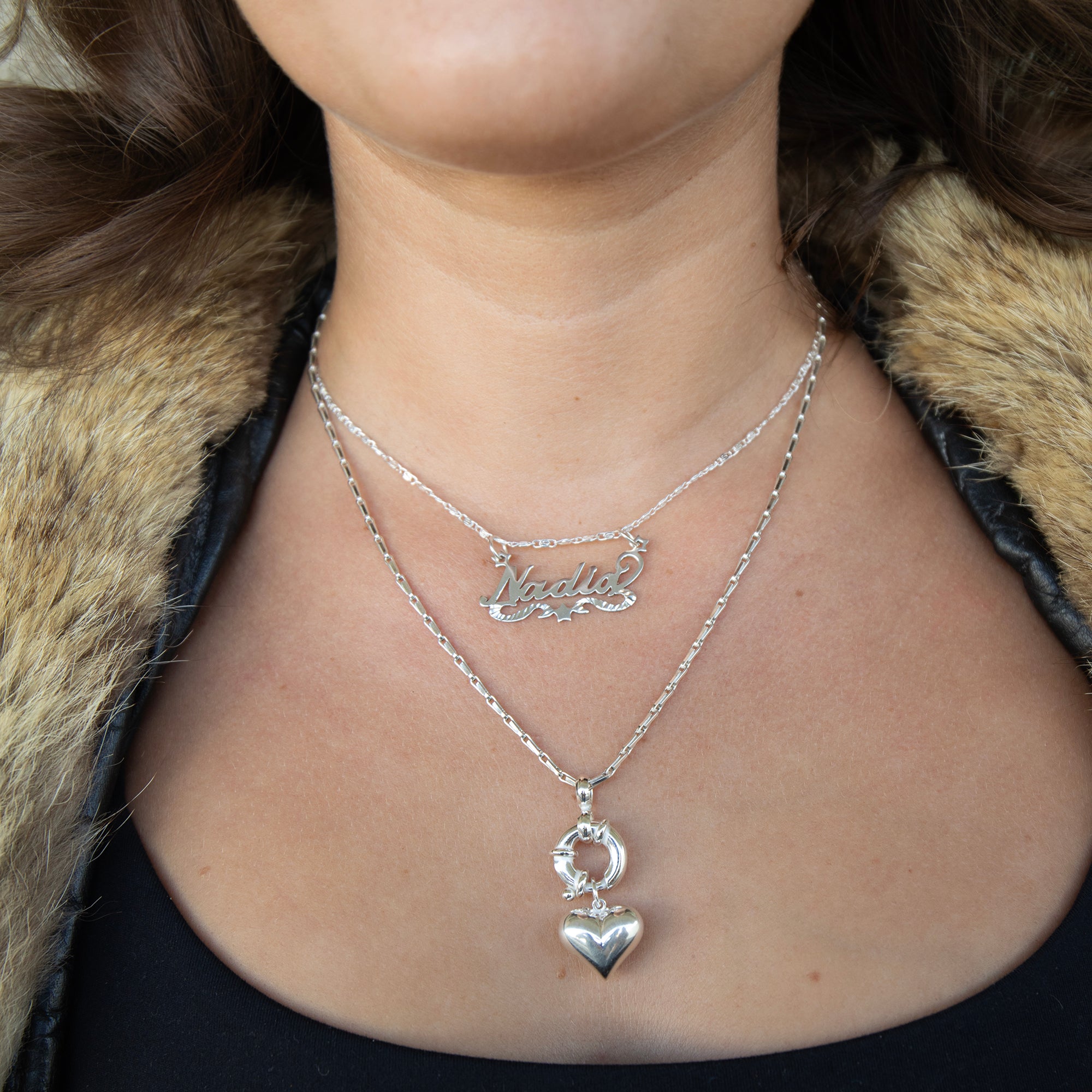 Person wearing a silver necklace with a heart pendant and another necklace with engraved name - Sterling Silver Custom Script Star Name Pendant - seolgold