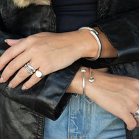 Close-up of hands wearing silver rings and bracelets on a black leather jacket - seolgold